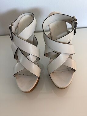 white leather Gucci sandals feature high platform an intricate crisscross strap